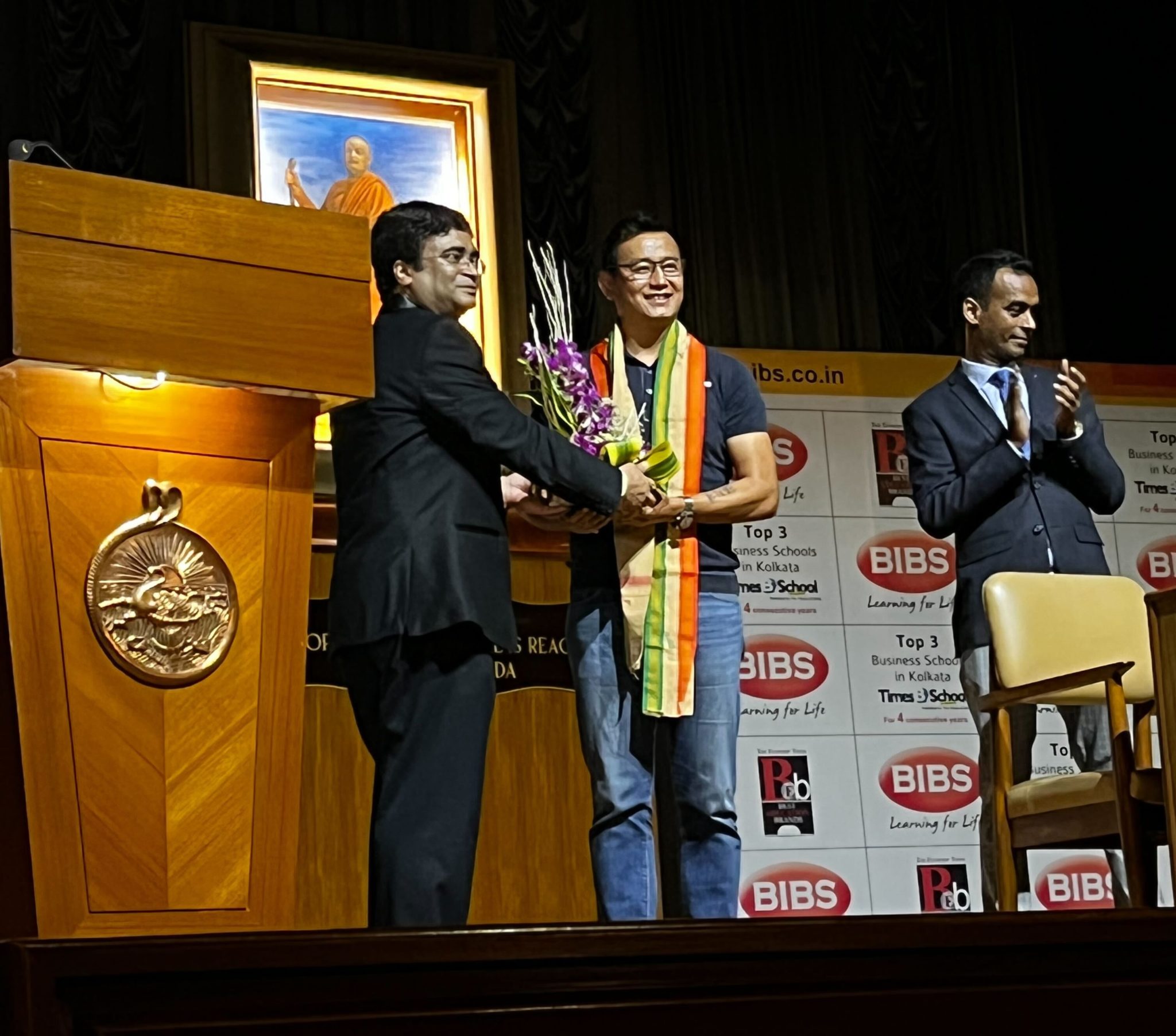 Bhaichung Bhutia is receiving a flower bouquet from BIBS Principal