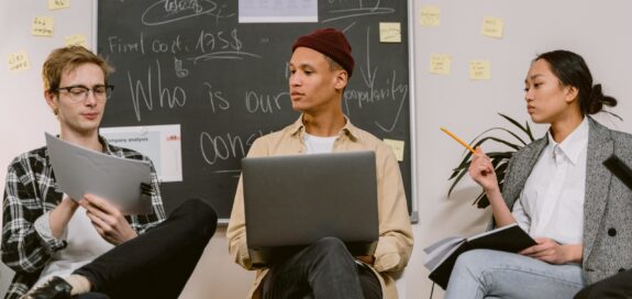 Three people are working on a laptop and understanding reports