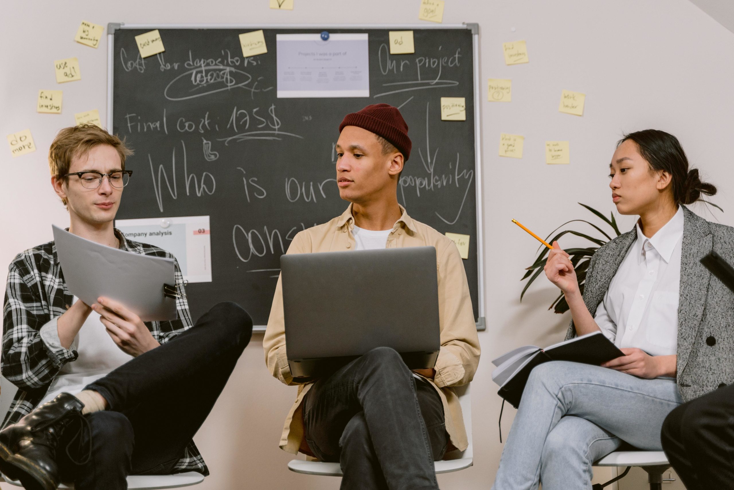 Three people are working on a laptop and understanding reports